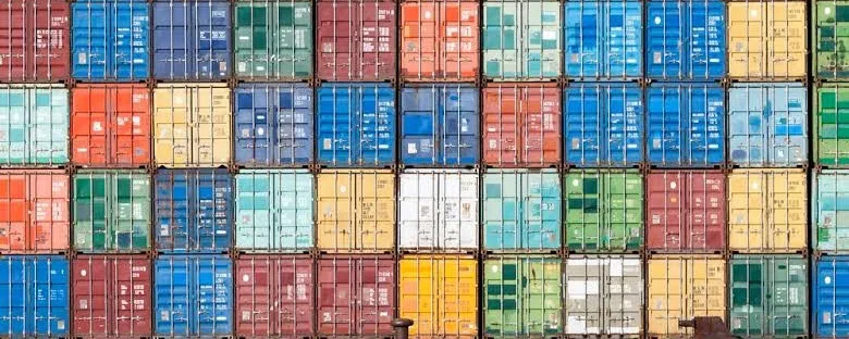 A wall of stacked shipping containers in many colours, filling the frame